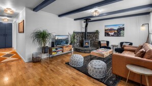 Uma sala de estar moderna com lareira de pedra, soalho em madeira e sofá de couro.