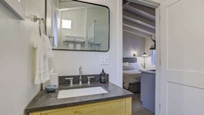 Een moderne badkamer met een grote spiegel, een wastafel en een houten kastje.