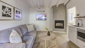 A modern living room with a grey sofa, a round wooden coffee table, and a fireplace. - South Lake Chalet #5 (South Lake Tahoe)