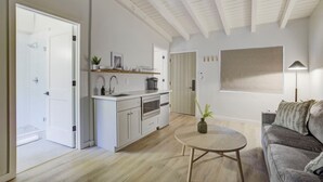 A modern kitchen with white cabinets, a central island, and a dining area with a round table. - South Lake Chalet #5 (South Lake Tahoe)