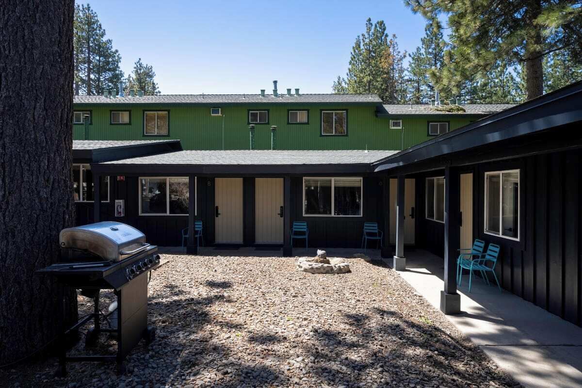 A building with a green exterior, a gravel patio, and a barbecue grill.