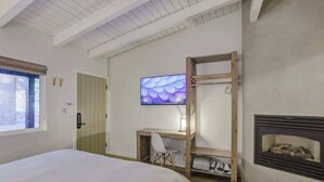 A bedroom with a bed, a desk, a chair, a television, and a fireplace. - South Lake Chalet #7 (South Lake Tahoe)