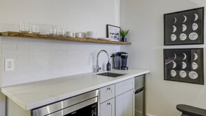 A modern kitchen with white cabinetry, stainless steel appliances, and a wooden shelf above the sink. - South Lake Chalet #7 (South Lake Tahoe)
