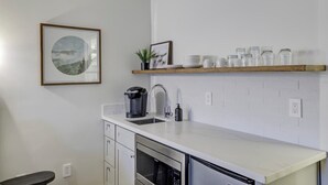 A modern kitchen with white cabinetry, a stainless steel microwave, a coffee maker, and a shelf with glass jars. - South Lake Chalet #8 (South Lake Tahoe)