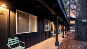 A building with large windows, a covered outdoor area with a bench, and a tree. - South Lake Chalet #11 (South Lake Tahoe)