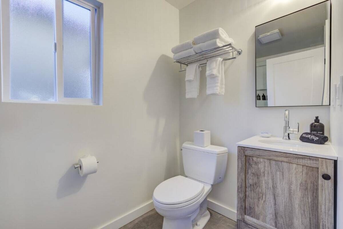 A bathroom with a toilet, a towel rack, a mirror, and a cabinet.