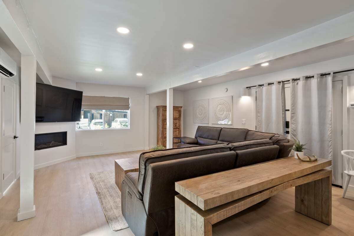 Una sala de estar moderna con un sofá seccional, una mesa de centro de madera y un televisor de pantalla plana montado en la pared.