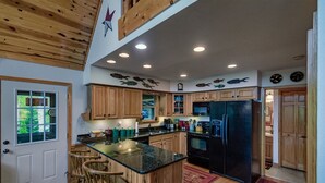A kitchen with wooden cabinets, a black refrigerator, and a central island with bar stools. - Patriot's Point Secluded Vacation escape (Bryson City)
