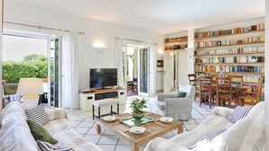 Ein geräumiges Wohnzimmer mit einer Couch, Sesseln, einem Couchtisch und einem Bücherregal.