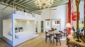 Een modern interieur met een bed in loftstijl, een eethoek met een ronde tafel, en een kroonluchter.