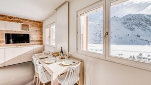 A modern kitchen with a dining area, large windows with a mountain view, and a wooden accent wall. - 100m from ski slopes, 5th floor, view lake/mountain, tv, ski locker, 35m², Tignes (Tignes)