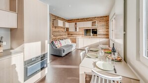 A modern kitchen with wooden accents, a dining area with a table set for two, and a grey sofa in the living area. - 100m from ski slopes, 5th floor, view lake/mountain, tv, ski locker, 35m², Tignes (Tignes)