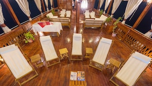 Una habitación con muebles de madera, incluyendo sillones y mesas, dispuestas en círculo.