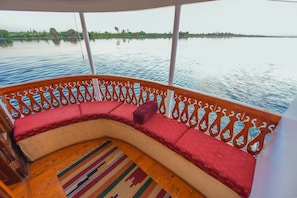 A boat deck with a curved seating area, a patterned rug, and a railing with intricate designs.