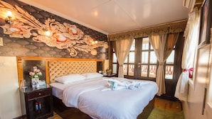 Habitación de hotel con una cama grande, una mesita de noche con espejo y un panel decorativo en la pared.