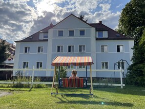 Ein mehrgeschossiges Wohngebäude mit weißer Fassade und roten Ziegeln.