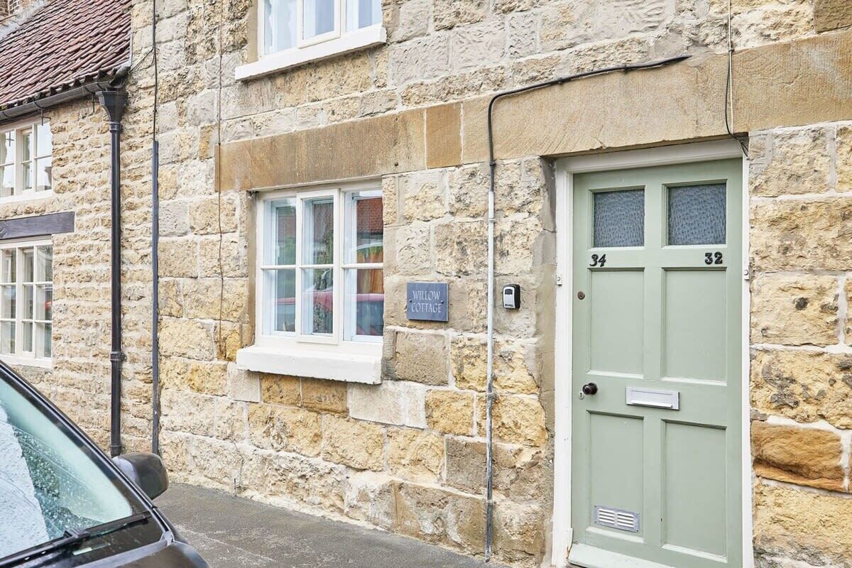 Un bâtiment en pierre avec une porte verte portant les numéros « 34 » et « 32 ».
