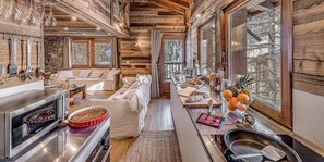 Cozy cabin with a central living area, dining table, and modern kitchen with a sofa and kitchen appliances.