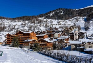 Surrounded by snow-covered slopes, this mountain village offers cozy accommodations with multi-story buildings and balconies.