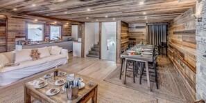 Relax in a warm and inviting space with a comfortable sofa, dining table, and wooden accents.
