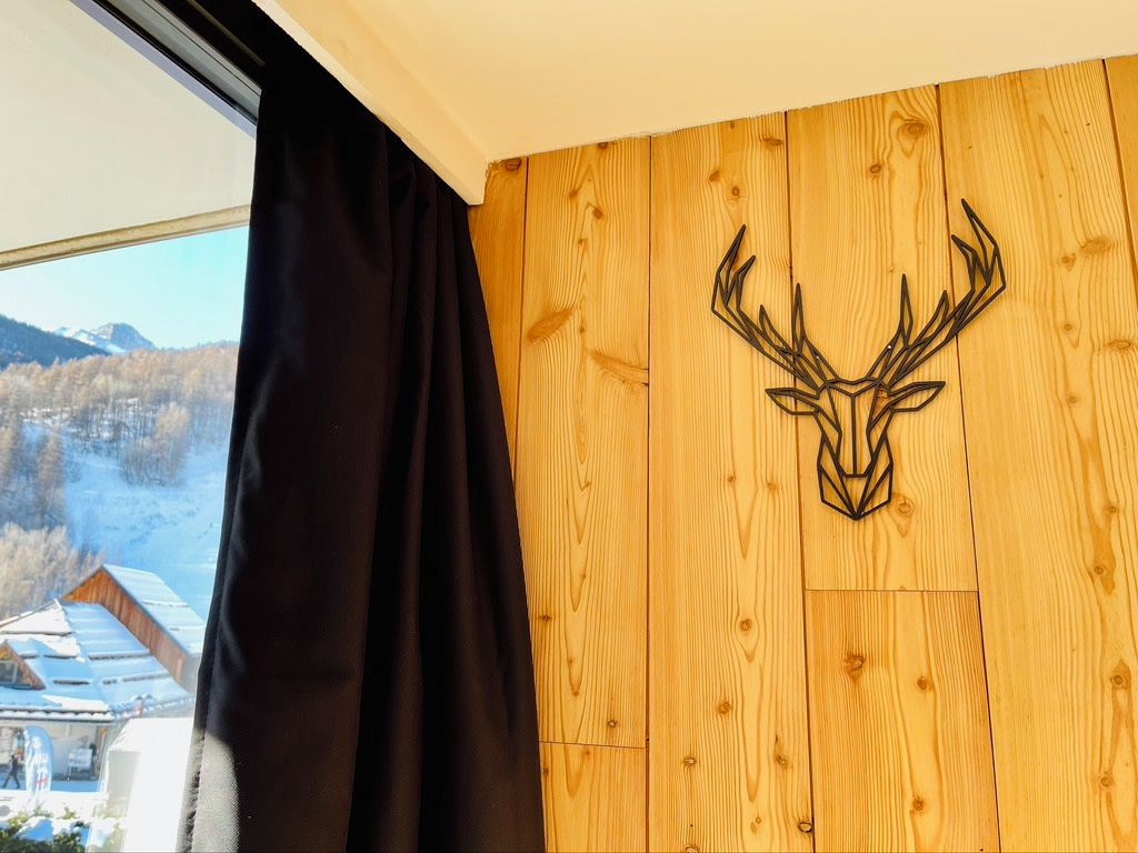 A room with a wooden wall and a deer head decoration.