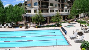 A hotel with a swimming pool, outdoor seating, and a large building with multiple balconies. - Highlands Slopeside #207 3 Bedroom Condo by RedAwning (Avon)