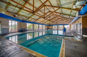 An indoor swimming pool with clear water, wooden beams on the ceiling, and exercise equipment along the side. - Statuesque waterfront home by Seaside Vacations & Sales (Greenbackville)