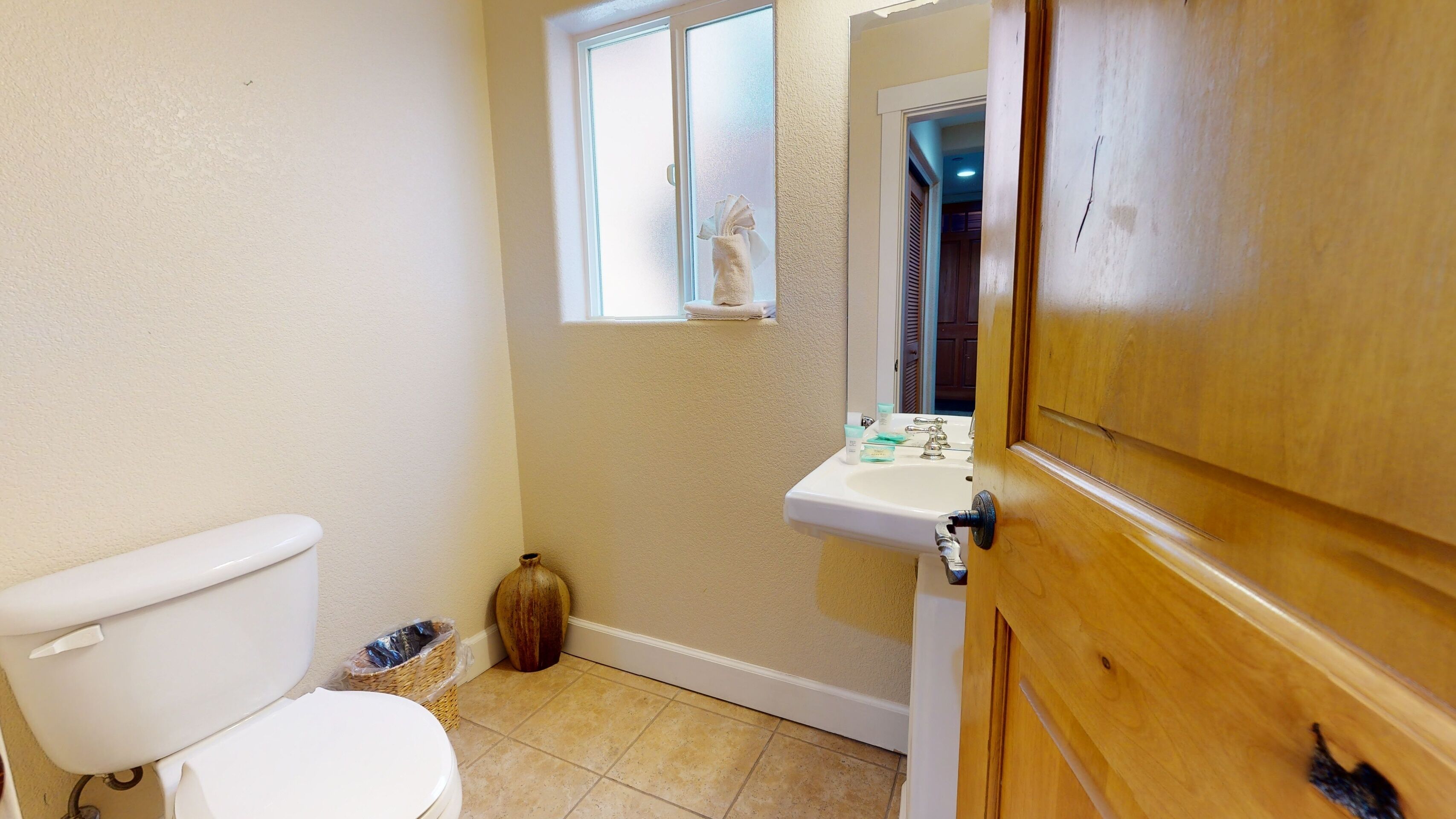 Une petite salle de bain avec des toilettes, un lavabo et une fenêtre.