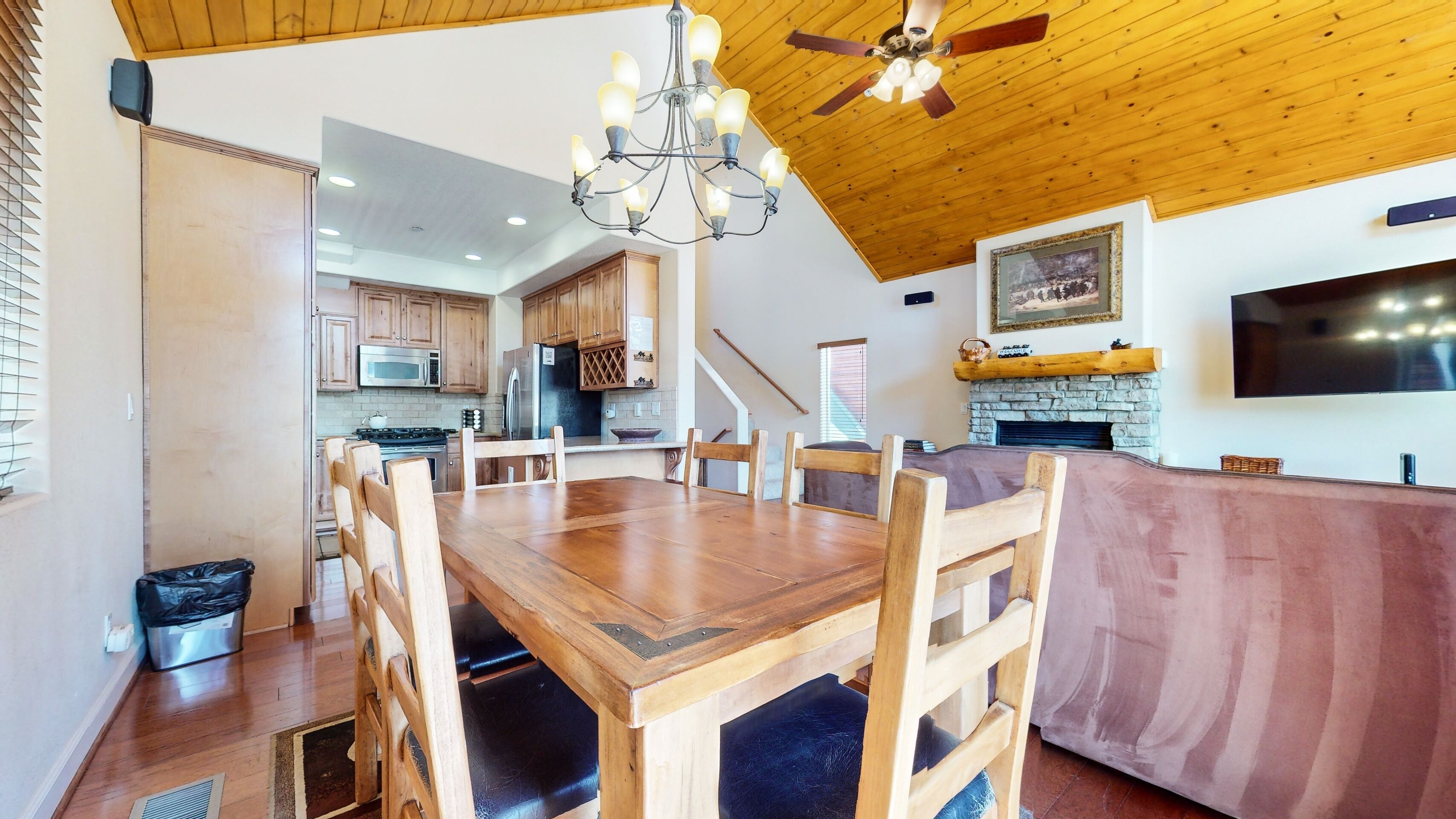 A spacious kitchen with wooden cabinets, a dining table, and a stone fireplace.