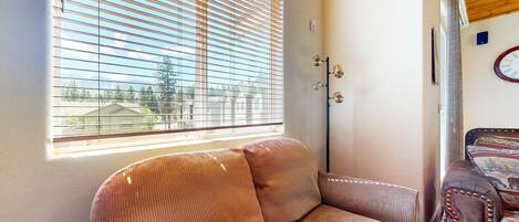 A room with a large window, a sofa, a lamp, and a clock on the wall.
