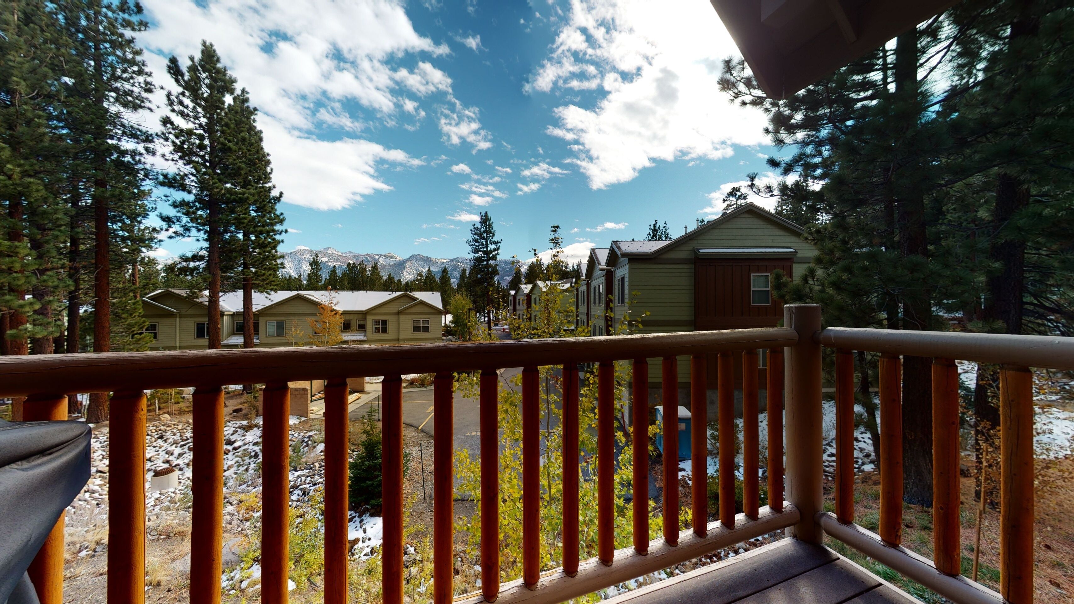 A wooden deck with a view of cabins and mountains.