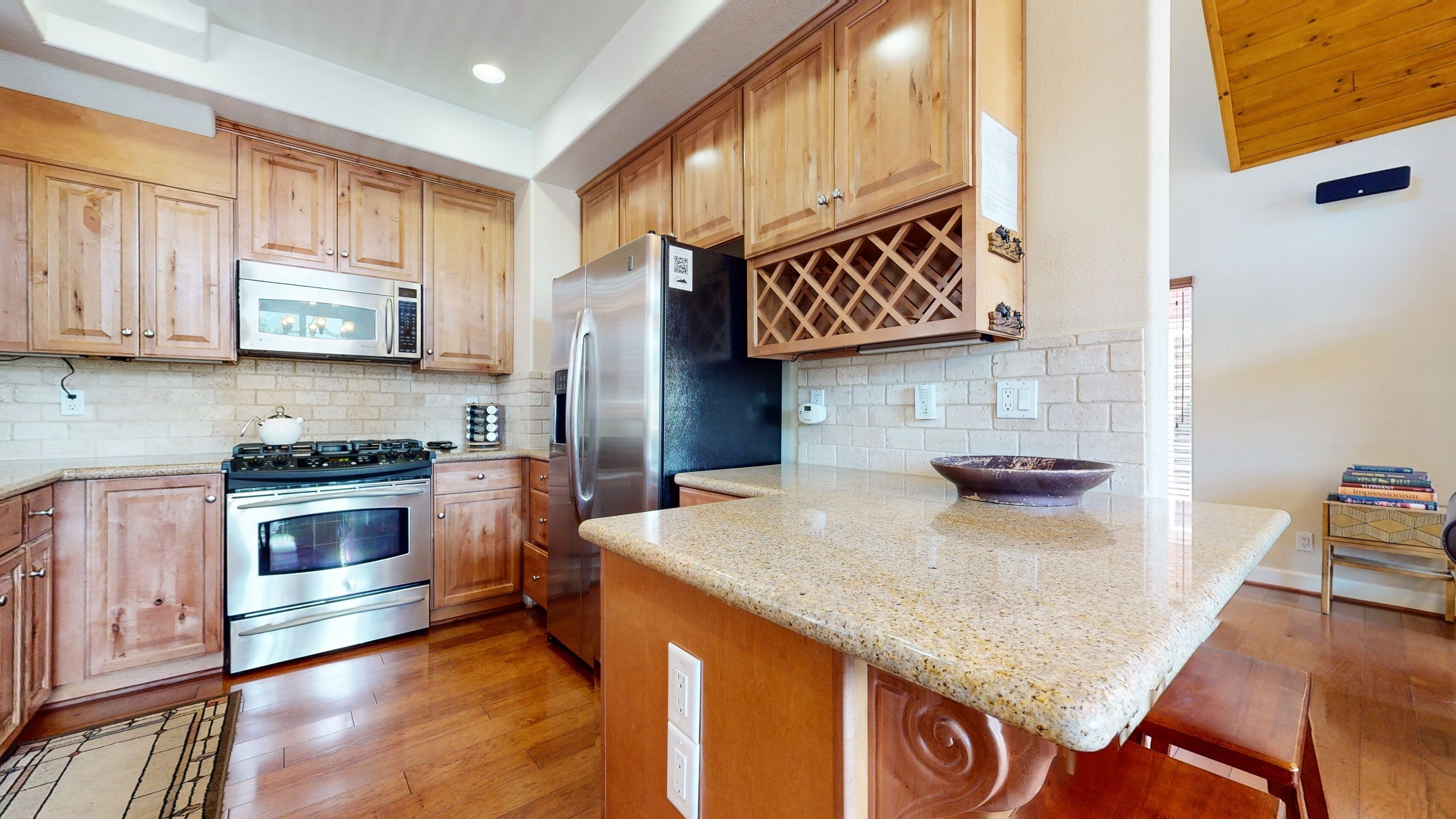 A kitchen with wooden cabinets, stainless steel appliances, a granite countertop, and a built-in wine cooler.