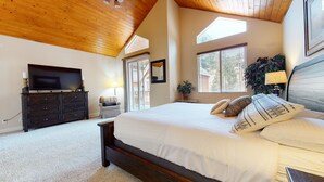 A bedroom with a large bed, a TV, a dresser, and a window with blinds. - Mammoth Gateway Village 7 Pet-Friendly, Mountain Modern with Private Jacuzzi and 2 Car Garage by RedAwning (Mammoth Lakes)