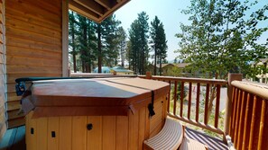 A wooden deck with a hot tub, wooden railings, and a view of surrounding trees and buildings. - Mammoth Gateway Village 7 Pet-Friendly, Mountain Modern with Private Jacuzzi and 2 Car Garage by RedAwning (Mammoth Lakes)