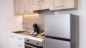 A kitchen with wooden cabinets, a stainless steel refrigerator, a coffee maker, and a sink. - Suite con Terrazzo, Parcheggio Gratuito – Lecce (Castromediano)