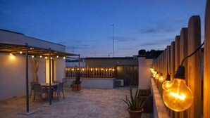 An outdoor patio area with a table and chairs, string lights, and a wooden fence. - Suite con Terrazzo, Parcheggio Gratuito – Lecce (Castromediano)
