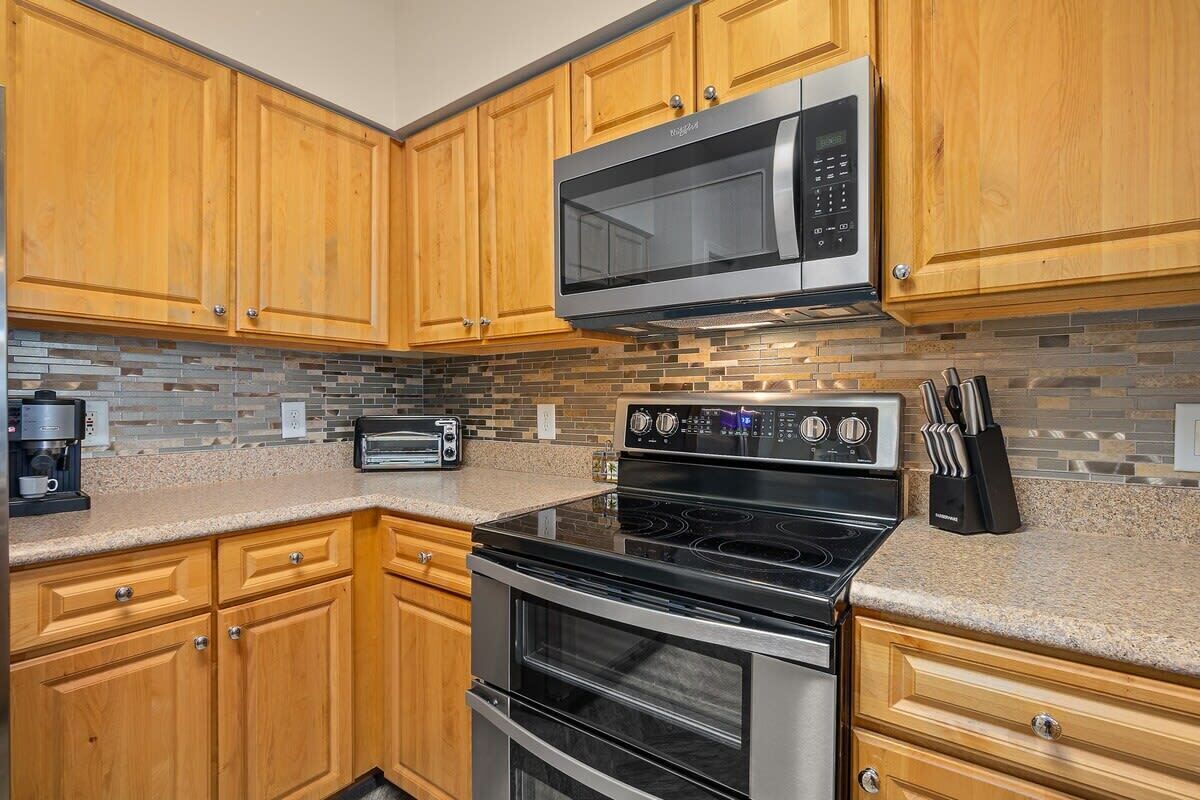 A kitchen with wooden cabinets, a microwave, a toaster, an oven, and a coffee maker.