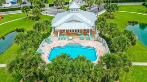 Une grande maison avec une piscine, entourée de palmiers et dotée d’une pelouse bien entretenue.