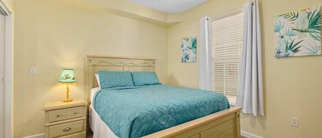 A bedroom with a bed, a nightstand, a ceiling fan, and two wall-mounted paintings.