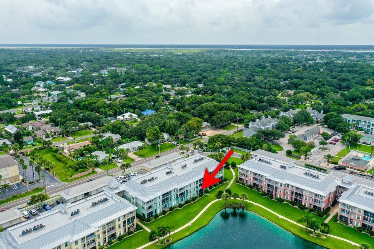 An aerial view of a residential area with a large building complex featuring multiple buildings, a central courtyard, and a body of water.