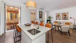Une cuisine moderne dotée d’un îlot central, un coin repas avec des chaises et un salon avec un canapé et une table basse.
