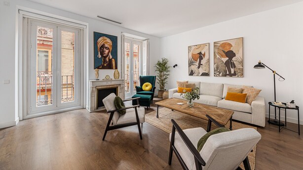 Un salon spacieux avec une cheminée, un ensemble de canapés, une table basse et des œuvres d’art accrochées aux murs.