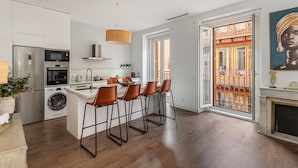 Une cuisine moderne dotée d’un îlot central, de tabourets de bar et offrant une vue sur un balcon agrémenté de balustrades décoratives.