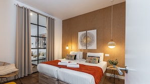 Une chambre moderne avec un grand lit, une table de chevet, une chaise et une vue sur le salon.
