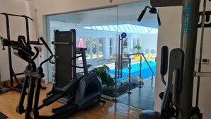 Una palestra domestica con attrezzature aerobiche e una porta in vetro che dà su un'area piscina.