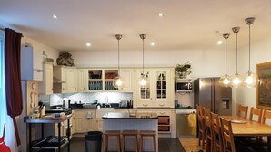 Una cucina moderna con mobili bianchi, un'isola centrale e luci a sospensione.