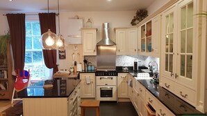 Una cucina moderna con mobili bianchi, un'isola centrale, elettrodomestici in acciaio inossidabile e vista sull'esterno.