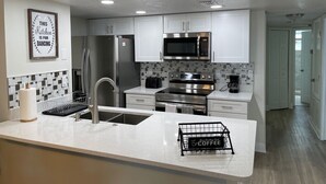 Una cocina moderna con armarios blancos, electrodomésticos de acero inoxidable y una zona de café.