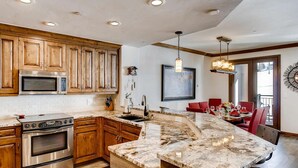 A kitchen with wooden cabinets, a built-in microwave, a stove, and a marble island. - Ski-In & Out Your Doorstep! Pool/Hot Tub, Great Village Access!! (Beaver Creek)