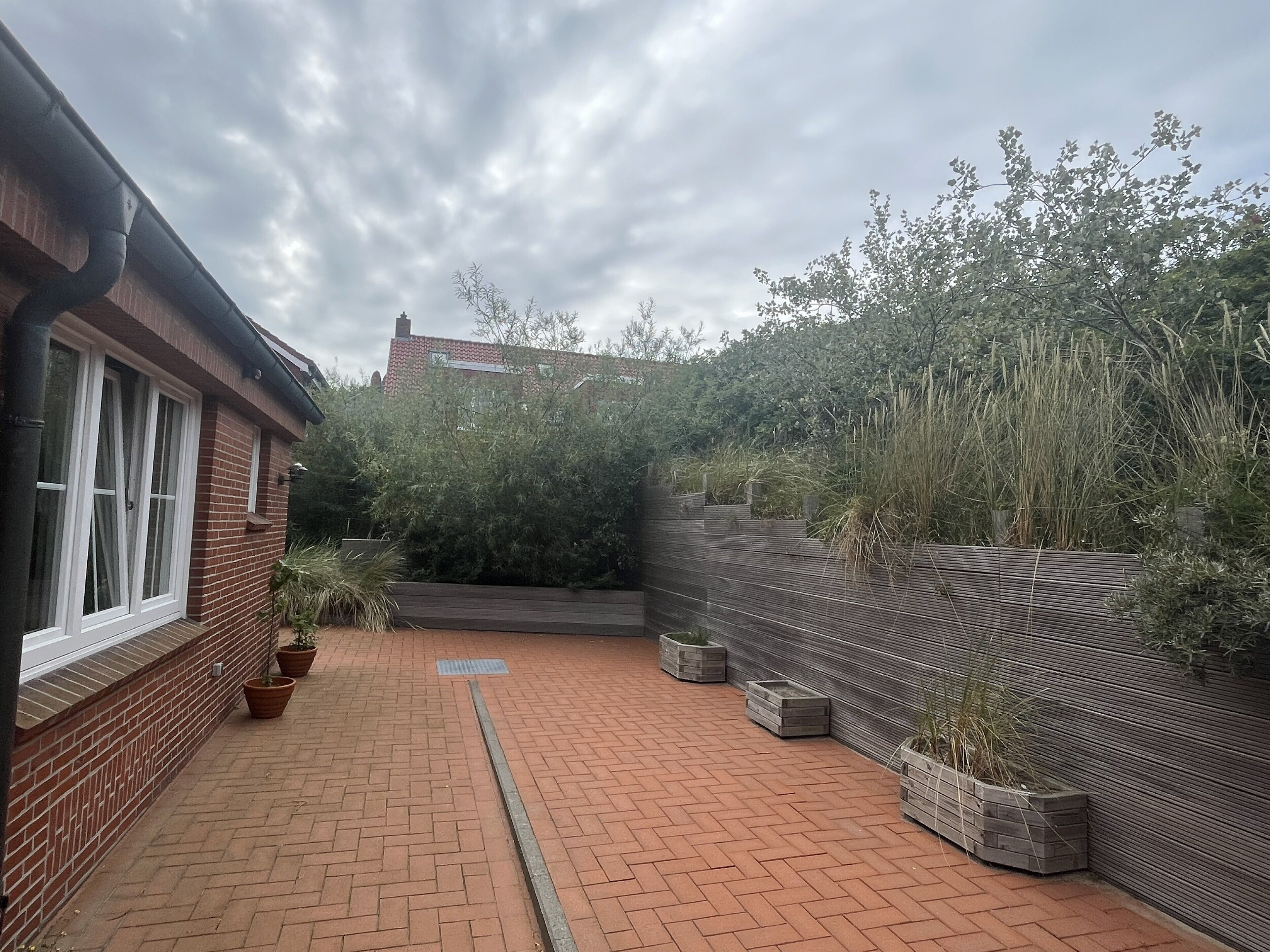 A brick patio with potted plants and a metal fence.